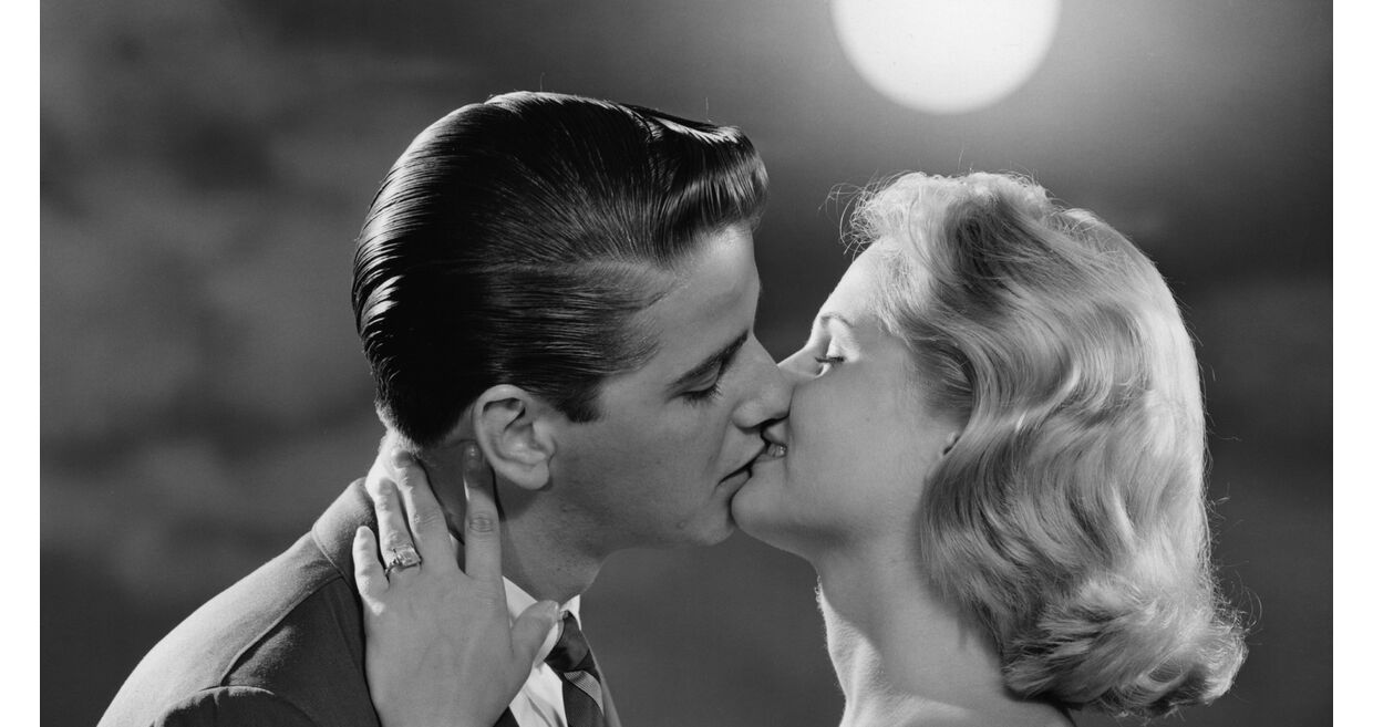 Casal apaixonado demonstra afeto sob a luz da lua, num ambiente romântico