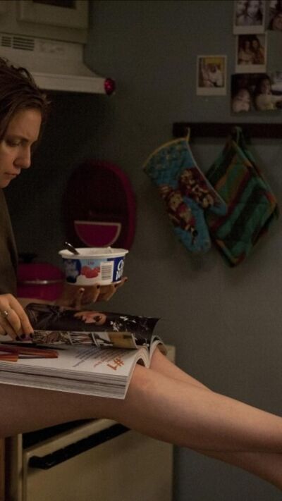 Mulher lê revista enquanto come iogurte