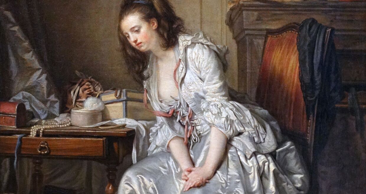 Mulher senta-se perto de mesa com objetos.
