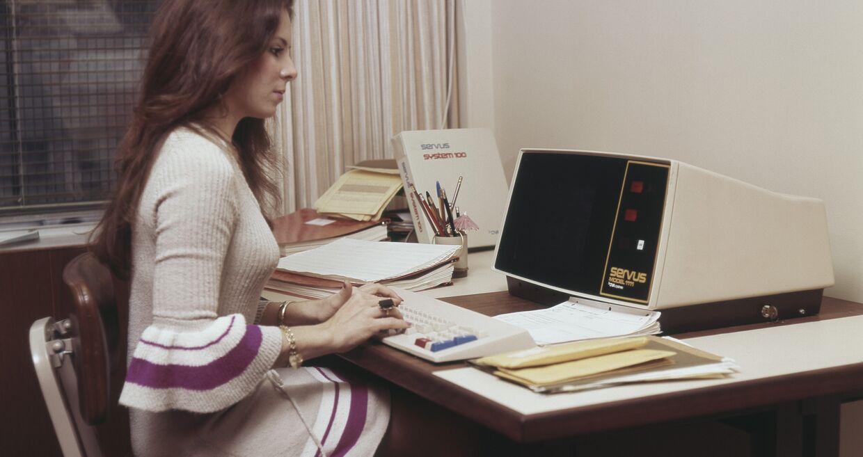 Mulher trabalha num computador Servus System 100, num escritório dos anos 70