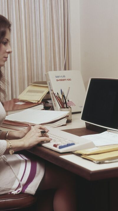 Mulher trabalha num computador Servus System 100, num escritório dos anos 70