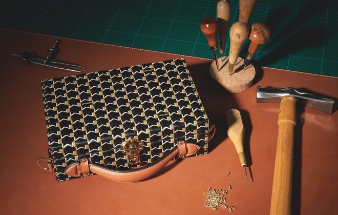 Preparação para a aplicação final de tachas numa mala de lona castanha tamanho M