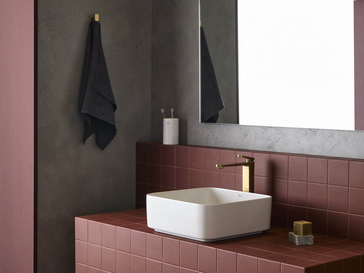 Torneira moderna destaca-se na casa de banho com azulejos vermelhos, espelho e toalha escura