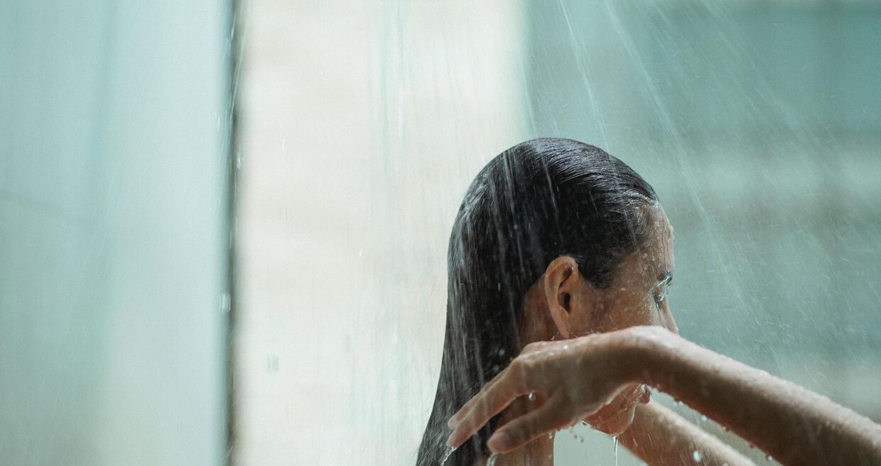 Mulher toma duche e lava o cabelo