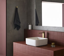 Torneira moderna destaca-se na casa de banho com azulejos vermelhos, espelho e toalha escura