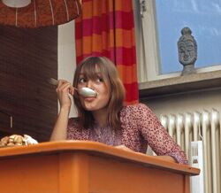 Mulher com colher na boca e mesa laranja num artigo sobre endometriose e dieta