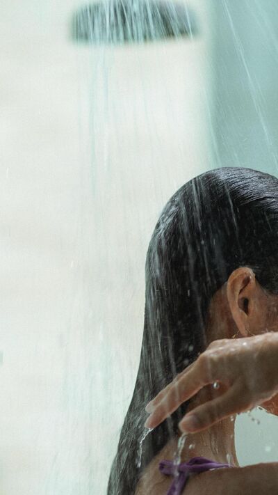 Mulher toma duche e lava o cabelo
