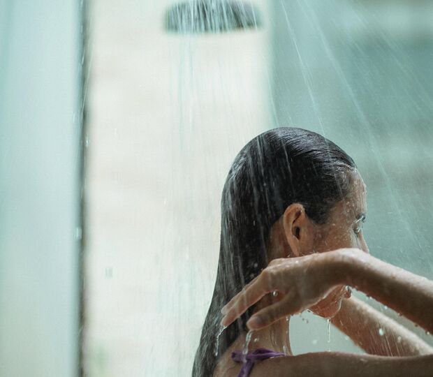 Mulher toma duche e lava o cabelo