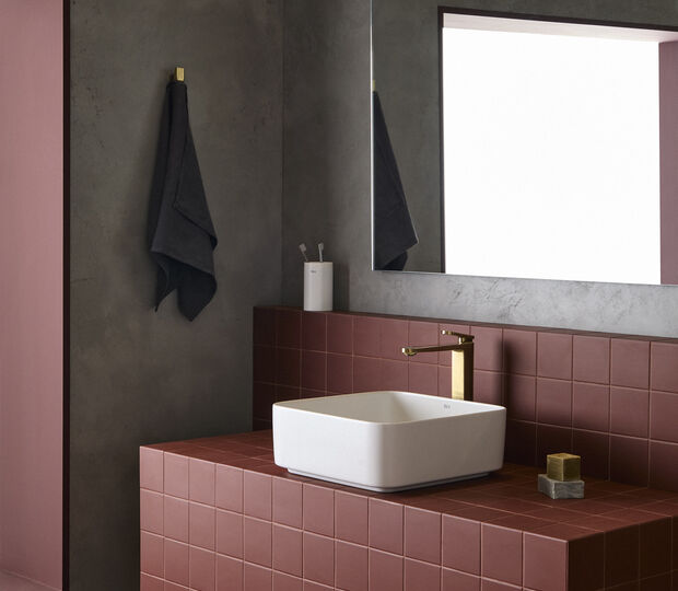 Torneira moderna destaca-se na casa de banho com azulejos vermelhos, espelho e toalha escura