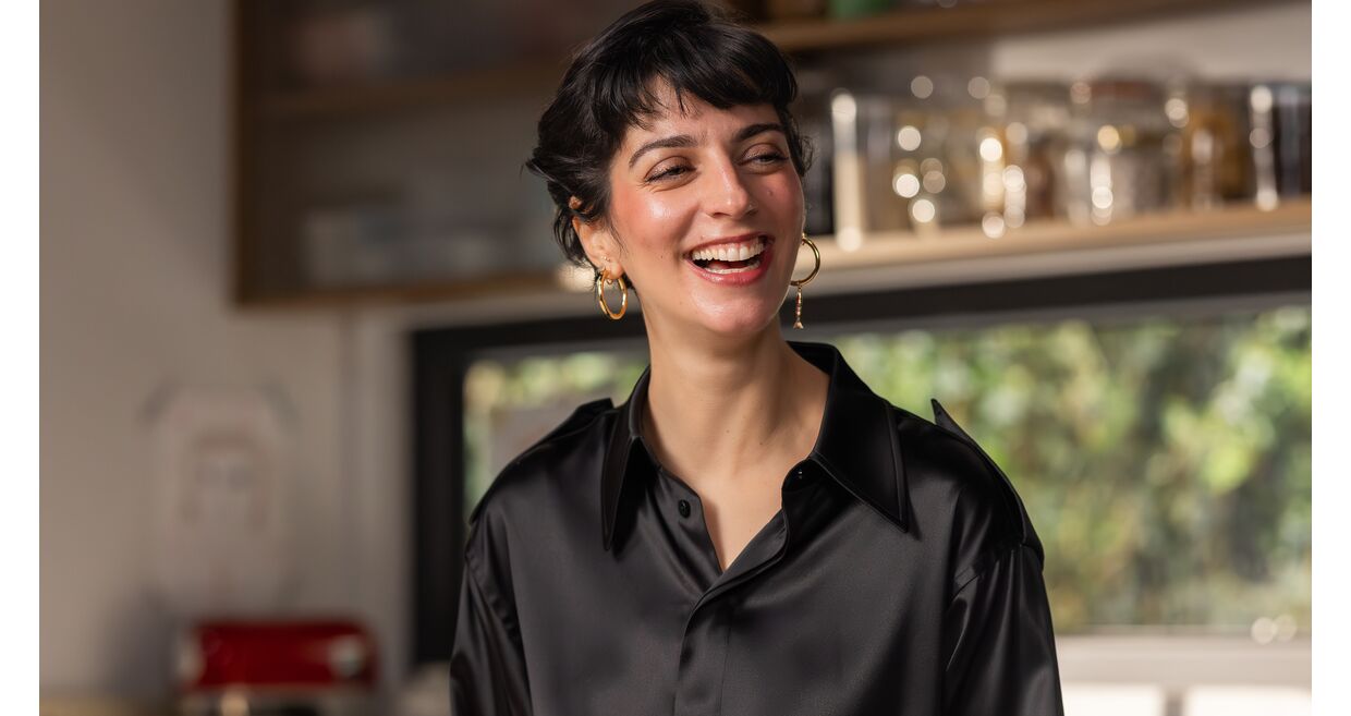 Joana Barrios prepara batata doce na cozinha, com um sorriso