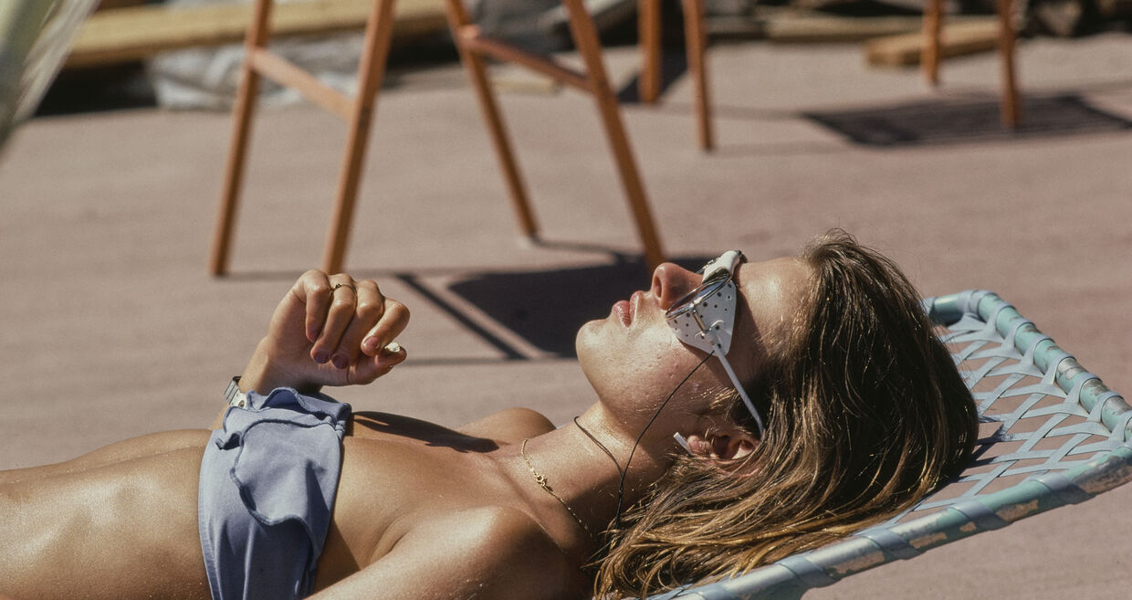 Mulher relaxa ao sol com óculos de proteção e roupa de banho