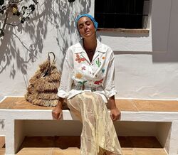 Mulher usa roupa com bordados de cactos e borboletas, combinada com saia de renda