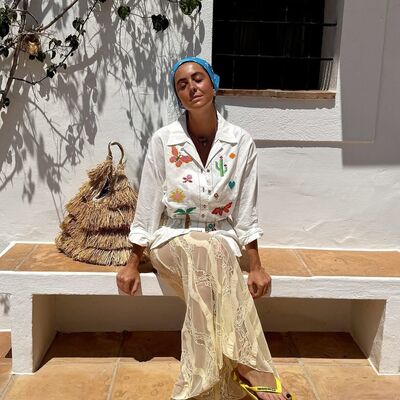 Mulher usa roupa com bordados de cactos e borboletas, combinada com saia de renda