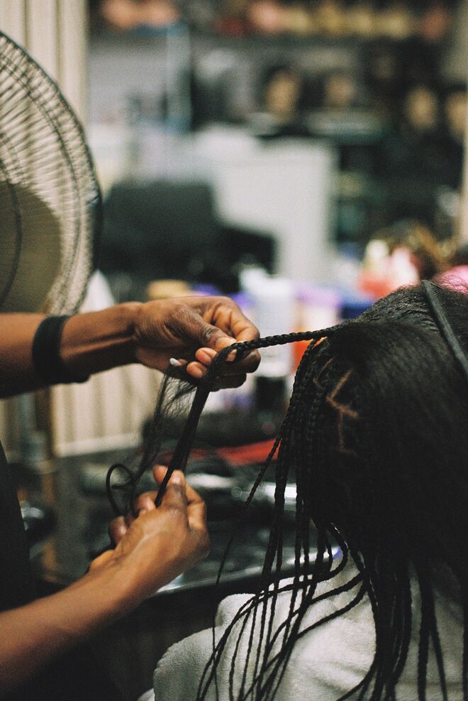 Mãos criam um penteado com tranças, um ato de beleza ancestral